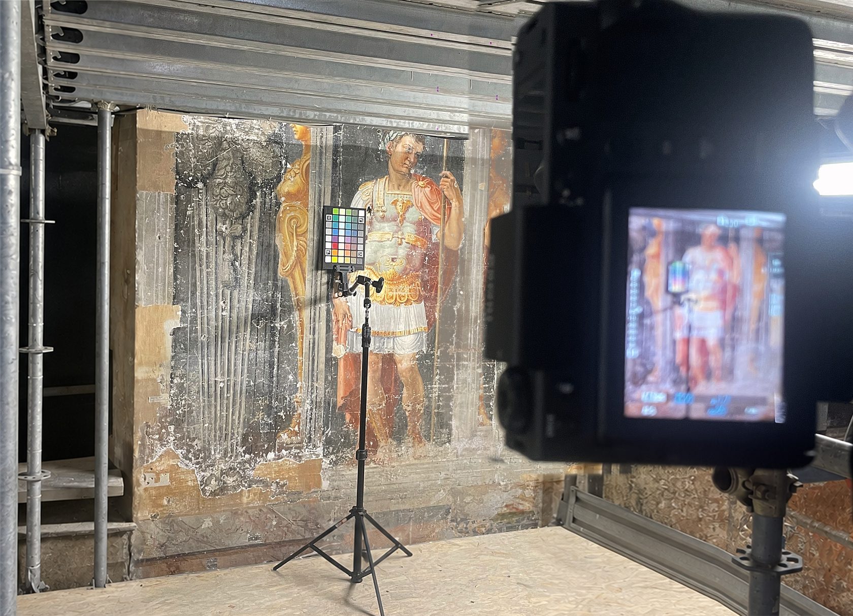 Colour documentation of a fresco: a colour reference target on a tripod in front of a painted Roman emperor, with a camera and studio light.
